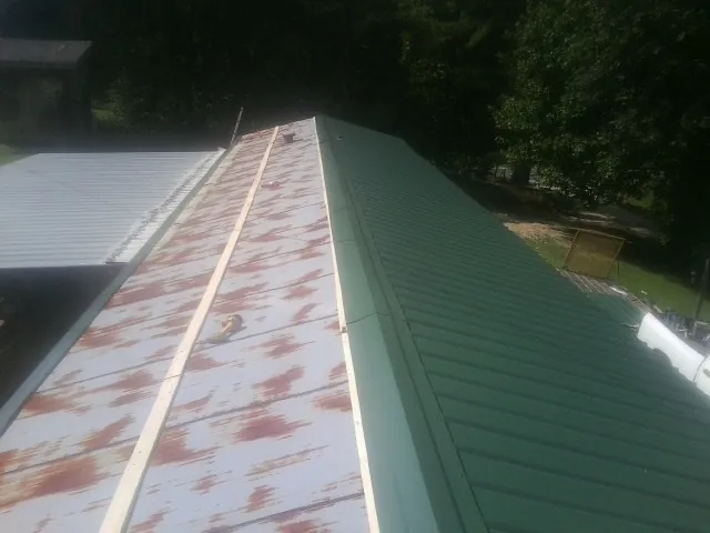 Old rusted panels beside newly installed green metal roofing — Wind Damage Roof Repair by Roofing Brothers in Chelmsford