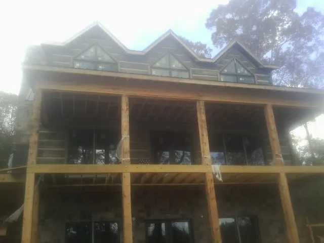 Dormers and porch framing on a large log home under construction — Roof Coating work by our crew in Chelmsford