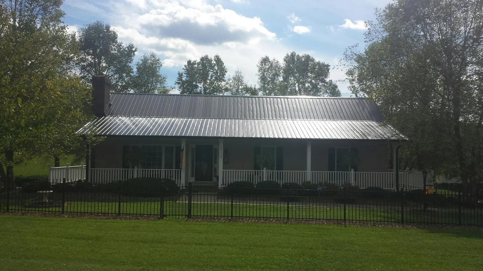 Gray metal roof on a brick ranch with a full width front porch — Gutter Guard Installation work by our crew in Chelmsford