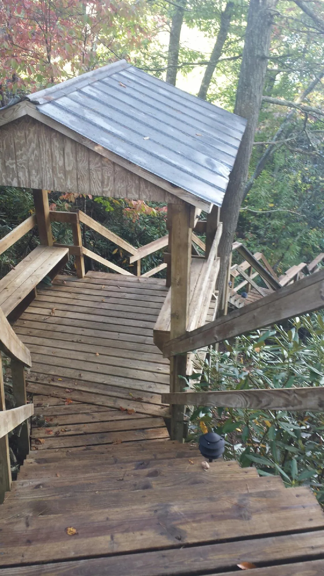 Metal roofed shelter over wooden steps on a wooded walkway — Skylight Repair & Installation work by our crew in Chelmsford