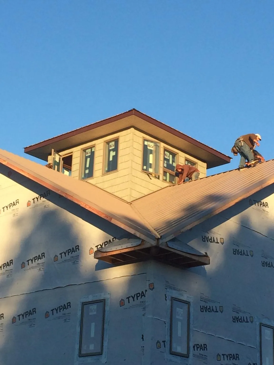 Roofers working around a rooftop cupola on a new metal roof at sunset — Roof Waterproofing in Chelmsford by Roofing Brothers